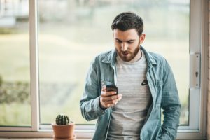 man holding phone - online dating response rate - Introverted Alpha