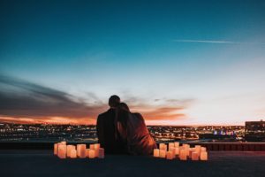 couple sitting on rooftop with candles - how to ask for a second date without sounding desperate