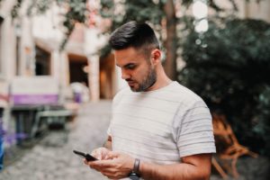 man looking at phone texting - how to subtly flirt with a girl over text