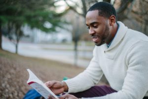 Man Reading Book Outside - How To Become A More Confident Man